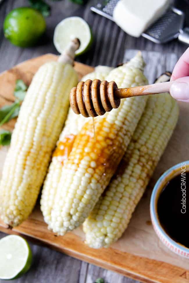 Pouring honey over Grilled Corn on the Cob with Chipotle Honey Lime Butter