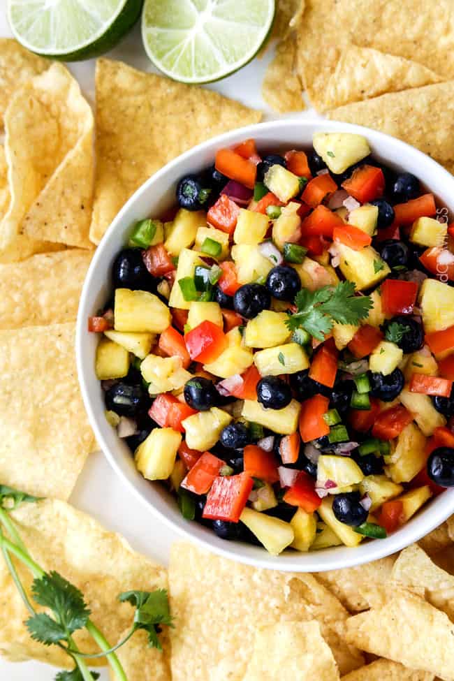 Top view of Blueberry Pineapple Salsa with a corn chips around the white bowl.