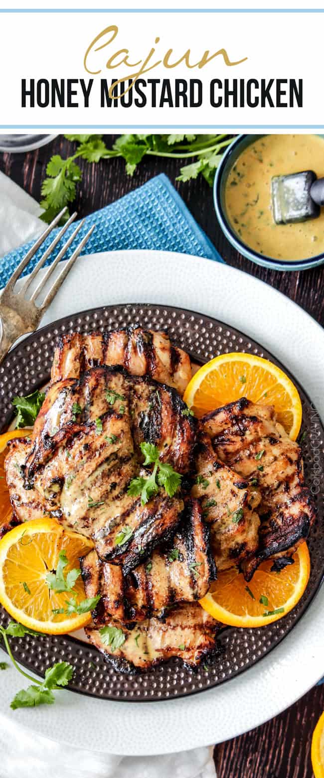 Cajun Honey Mustard Grilled Chicken on a brown plate with oranges a garnish and a serving fork. . 