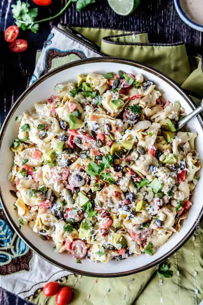 Make ahead, favorite potluck Southwest Pepper Jack Tortellini Salad = cheesy pillows of tortellini, sweet corn, black beans, avocado, bell peppers, etc. bathed in Creamy Salsa Dressing and garnished with bacon, Pepper Jack, sunflower seeds. Oh my YUM! #tortellini #pastasalad #southwest #salad