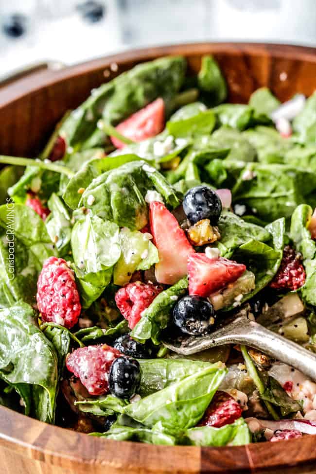 strawberry feta spinach salad tossed with poppyseed dressing in a large serving bowl 