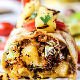 up close front view of a California Burrito with french fries, carne asada, sour cream and guacamole