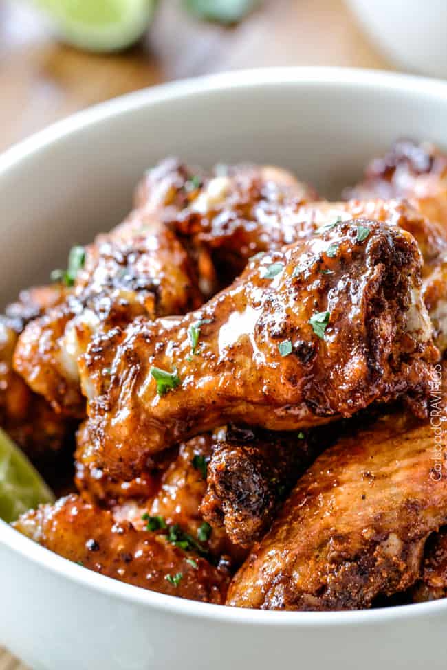 Close up of Baked Chipotle Honey Lime Hot Wings in a bowl with lime.
