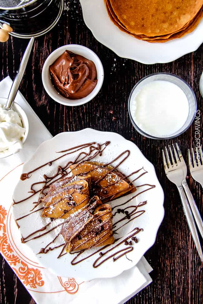 Nutella Pumpkin Crepes on a plate with powdered sugar. 