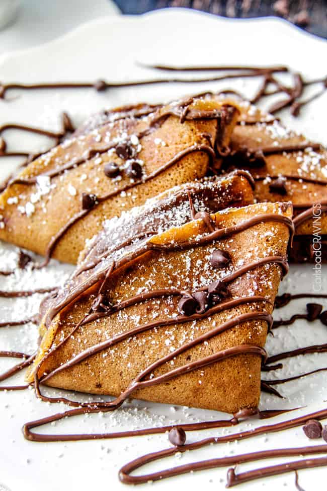 Nutella Pumpkin Crepes on a plate with powdered sugar and chocolate chips. 
