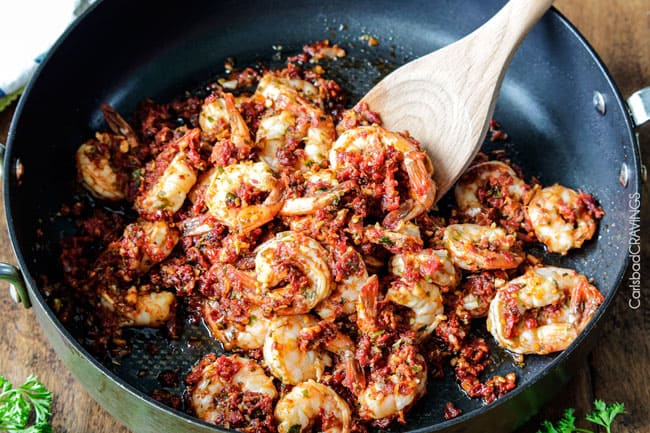 Showing how to make Sun-Dried Tomato Shrimp Pesto Pasta by cooking shrimp in pesto. 