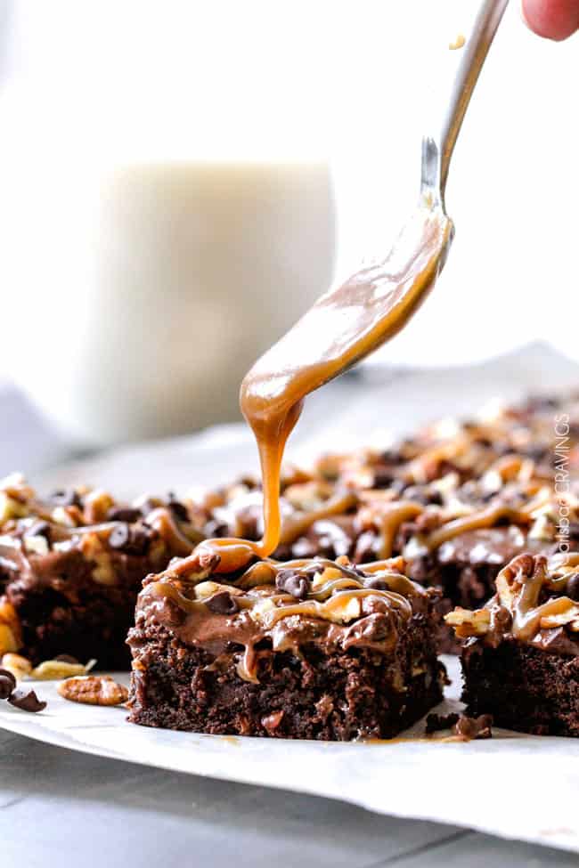 showing how to make Turtle Brownies by drizzling caramel over the top of the brownies with nuts and chocolate chips