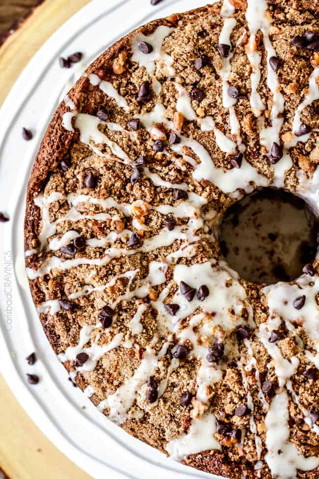 The best Banana ANYTHING ever! Moist Banana Coffee Cake riddled with chocolate chips and walnuts (optional) with an INCREDIBLY creamy cheesecake-like cream cheese filling all topped with brown sugar walnut streusel and vanilla drizzle.