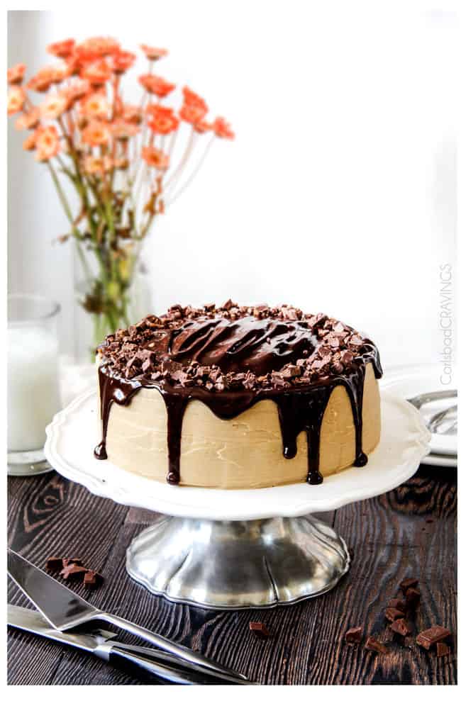 a salted caramel chocolate cake on a cake stand.