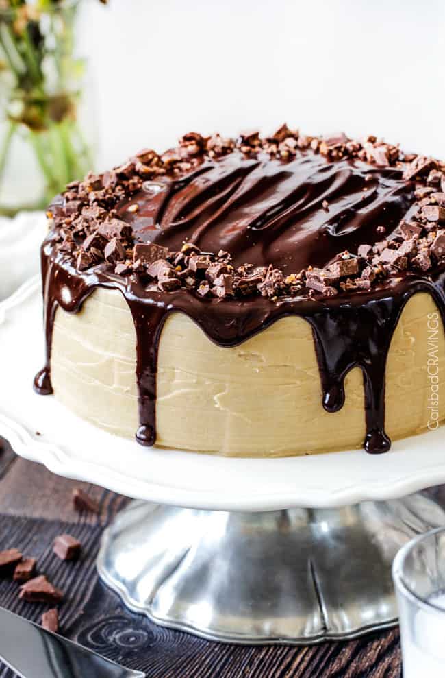 a salted caramel chocolate cake on a cake stand.
