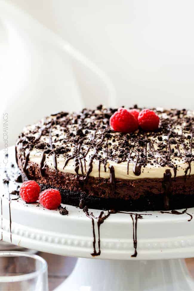 A full Peanut Butter Chocolate Mousse cake on a plate with raspberries.