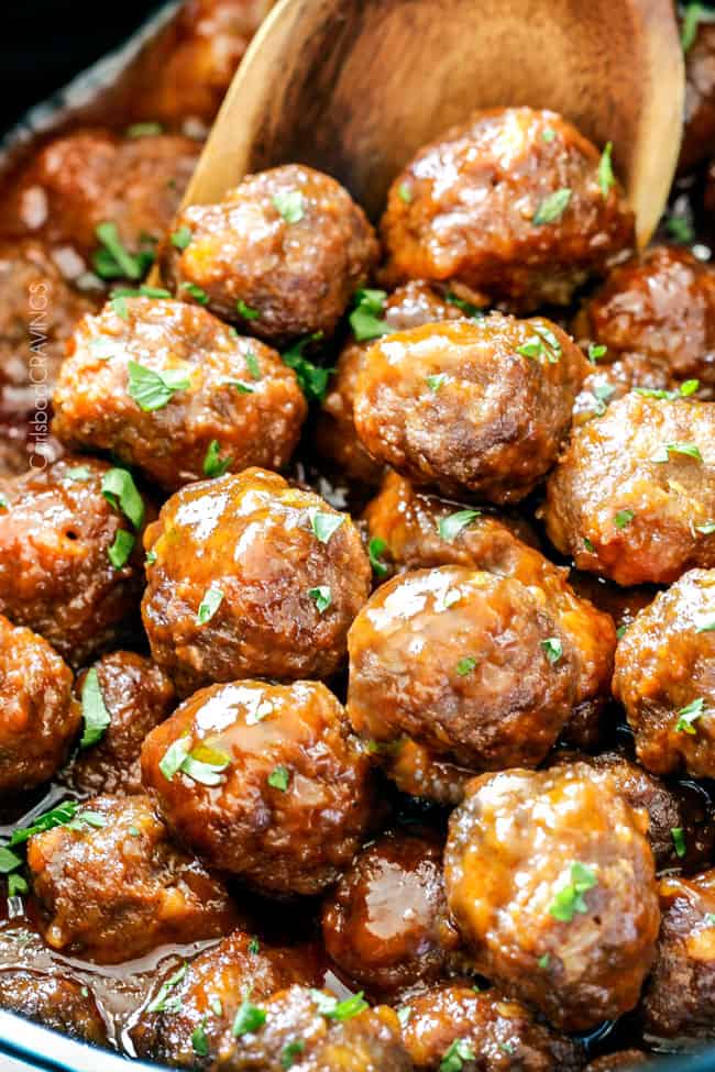 up close of scooping slow cooker buffalo meatballs in the crockpot with a wooden spoon