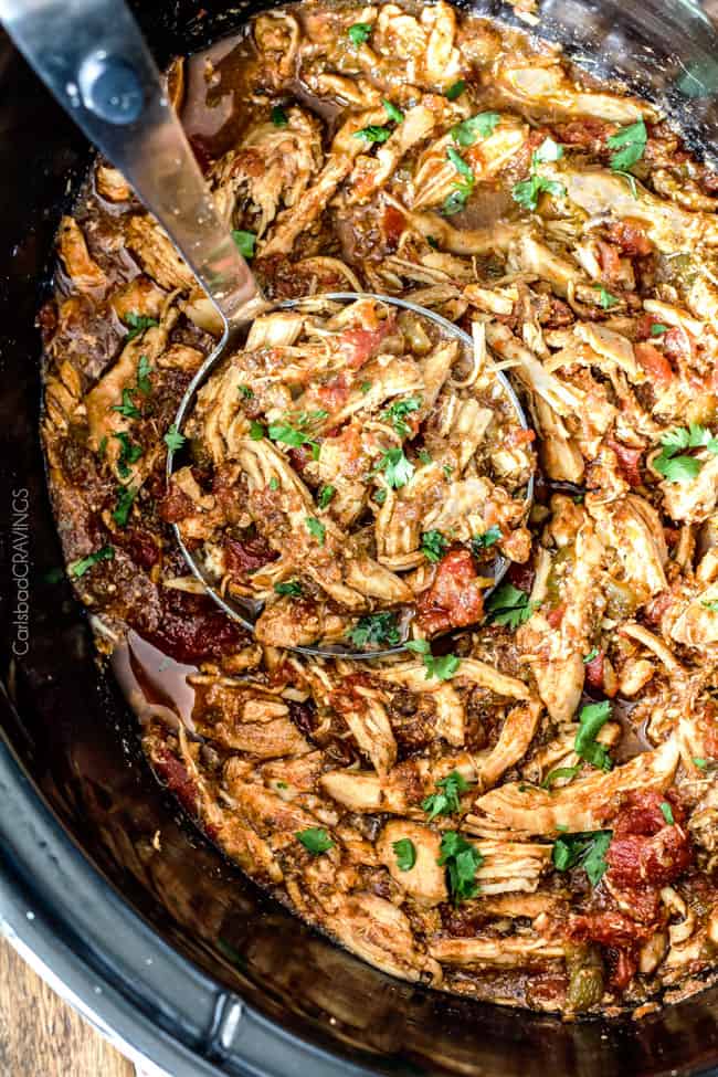 Shredded Mexican Chicken in the slow cooker being scooped out. 