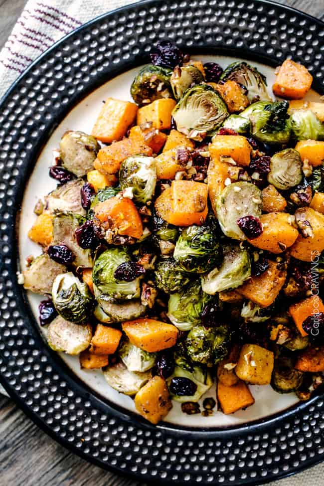 Easy Roasted Brussel Sprouts and Butternut Squash roasted in Dijon Maple Butter Sauce and tossed with cranberries and bacon for the BEST combo ever! tangy, salty, sweet, crunchy, crispy!