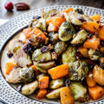 Easy Roasted Brussel Sprouts and Butternut Squash roasted in Dijon Maple Butter Sauce and tossed with cranberries and bacon for the BEST combo ever! tangy, salty, sweet, crunchy, crispy!