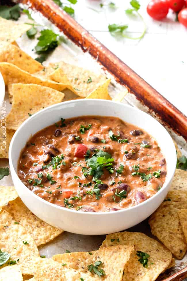 a bowl of chili cream cheese dip surrounded by chips