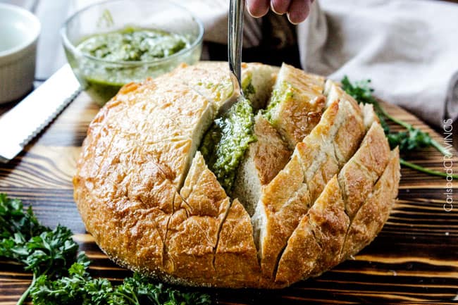 showing how to make pull apart bread by adding pesto in between the bread slices 