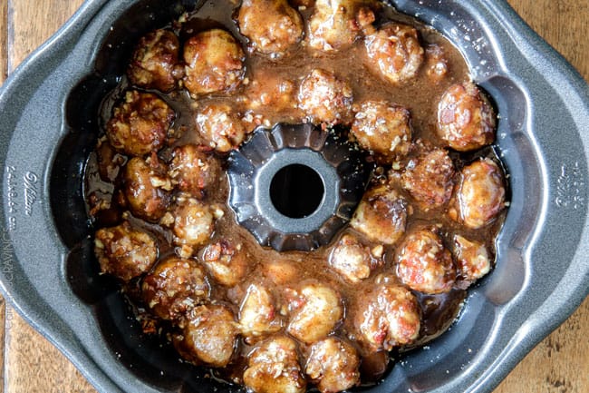 Showing how to make Cinnamon Roll Monkey Bread by pouring caramel all over dough balls in a bundt pan