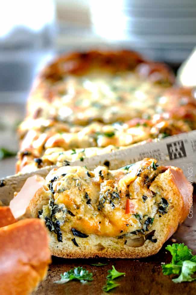 Close up showing a knife cutting Spinach Dip Stuffed French Bread