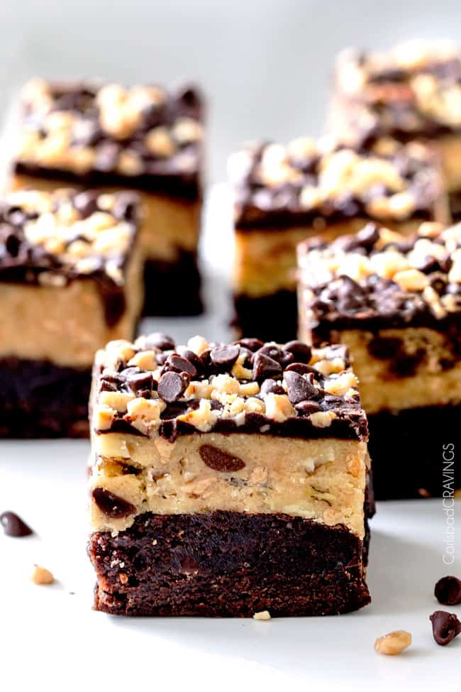 Several Toffee Chocolate Chip Cookie Dough Brownies with chocolate chips on the side. 