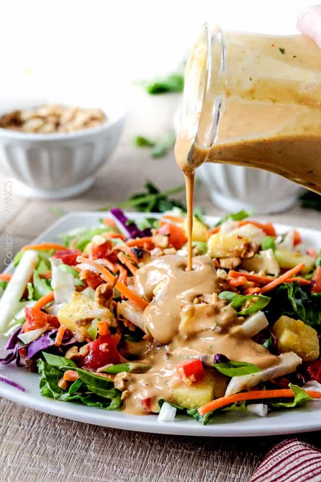 Thai peanut salad dressing being poured over a salad. 