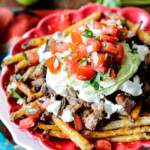 Forget the nachos, these Loaded Carne Asada Fries are so addictingly delicous! baked Mexican spiced French fries smothered in cheese and piled high with tender juicy steak, salsa, avocado crema, etc.