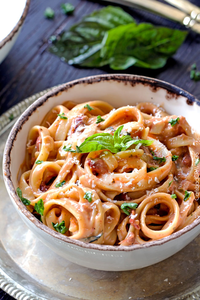 A bowl of Sun-dried Tomato Fettuccine Alfredo with basil on top.