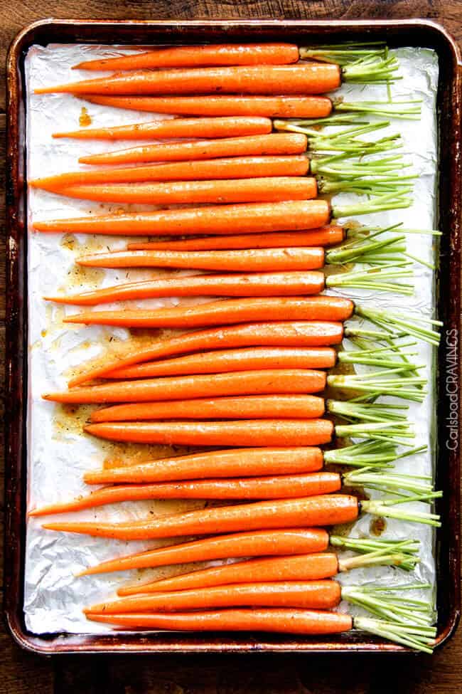 showing how to roast carrots in the oven by lining carrots up o a baking sheet