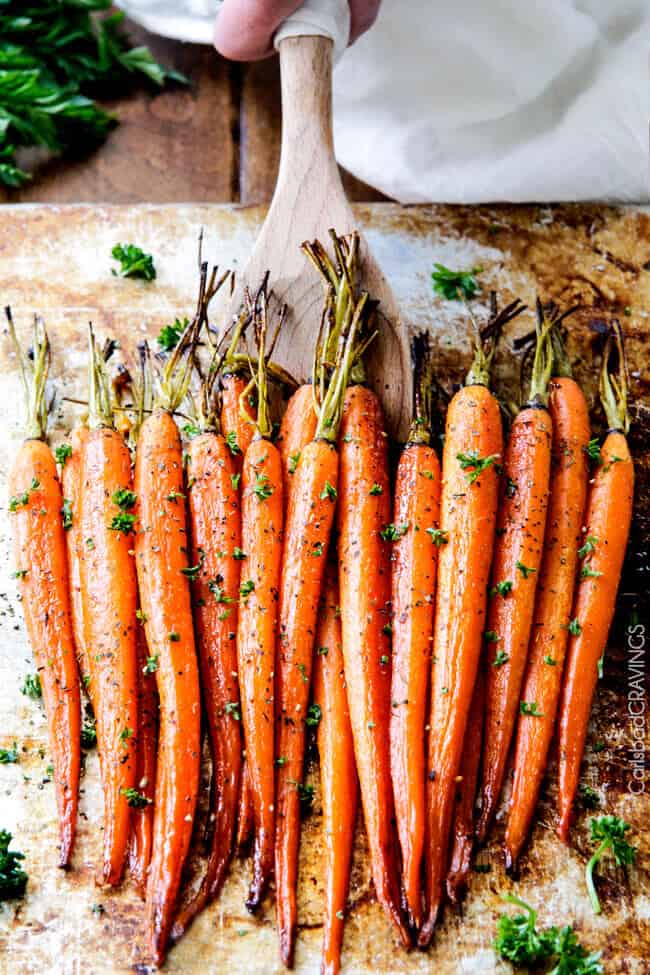 the best roasted carrots with honey on a serving platter with a wooden spoon
