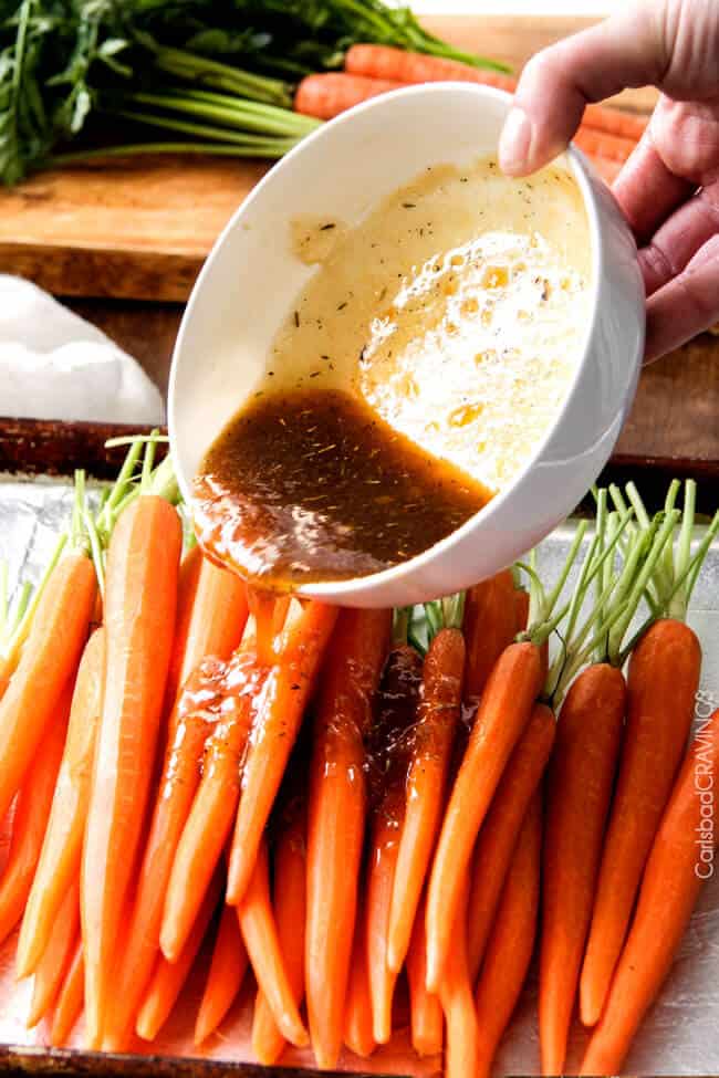 showing how to make roasted carrots by pouring honey glaze all over carrots