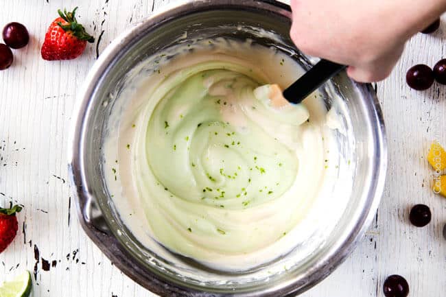 showing how to make cream cheese fruit dip by mixing cream cheese with yogurt