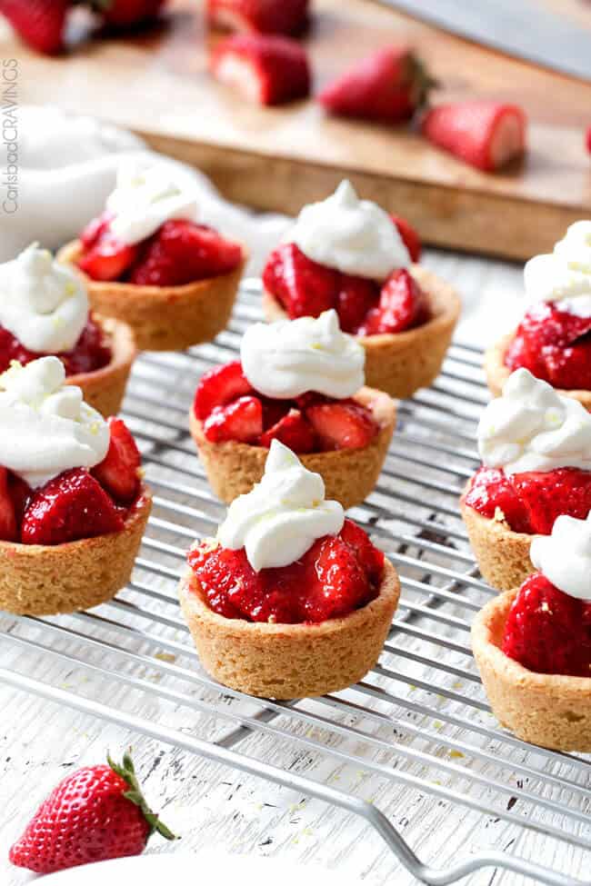 A cooling sheet of Mini Strawberry Pies with Sugar Cookie Crust with whipped cream on top.
