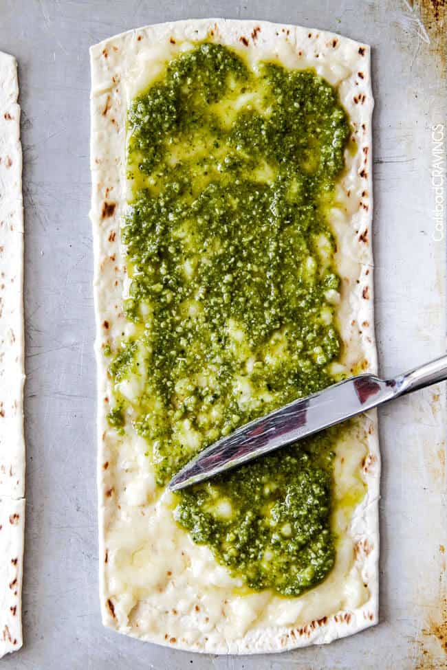 showing how to make Pear Gorgonzola Pizza recipe by layering pizza with pesto