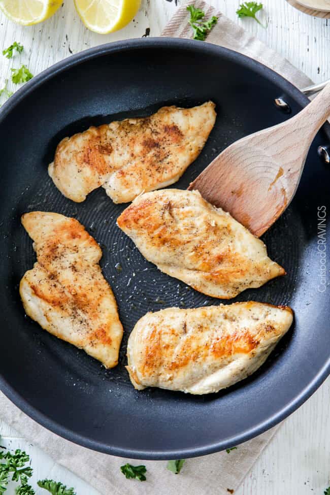 top view of four chicken breasts in a skillet. 