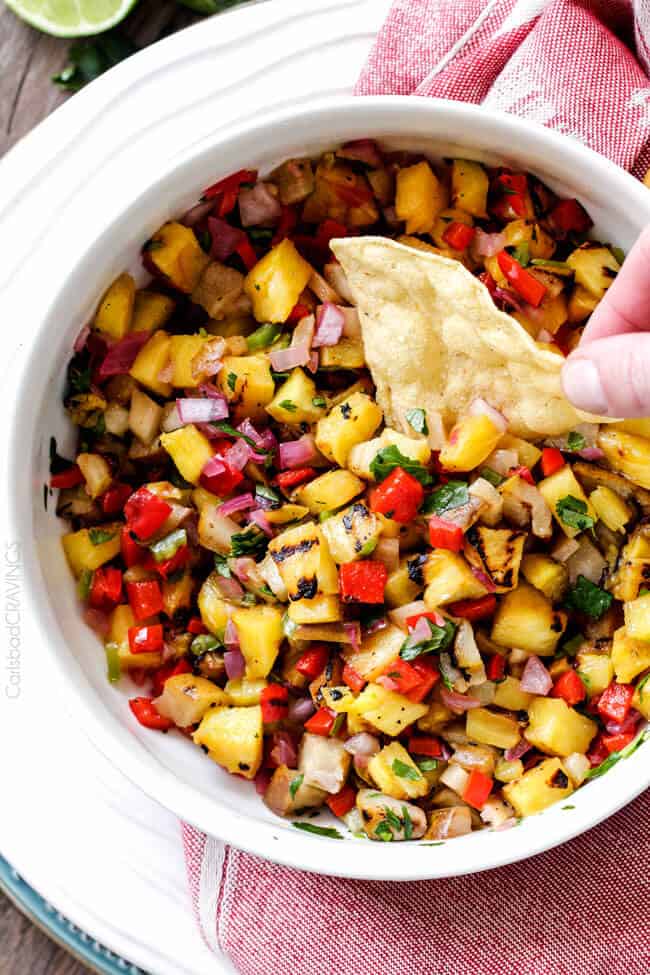 Top view of Grilled Pineapple Pear Salsa dipping a chip in.