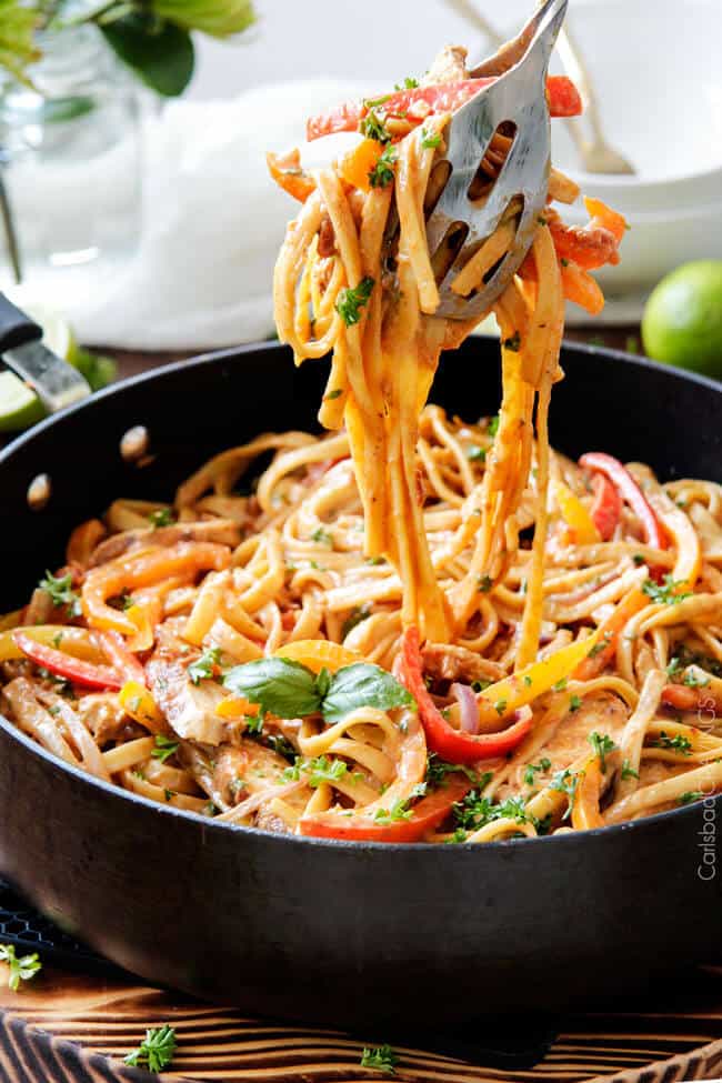 cajun chicken pasta in a large skillet being picked up with serving tongs. 
