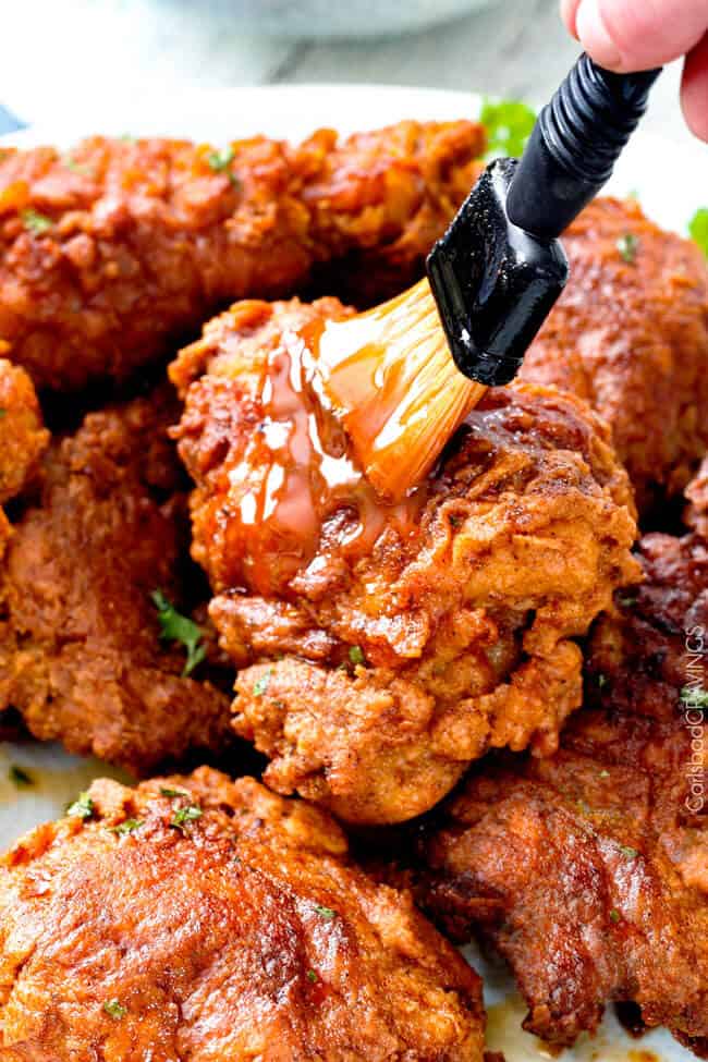 brushing nashville hot chicken sauce
onto pile of fried chicken 