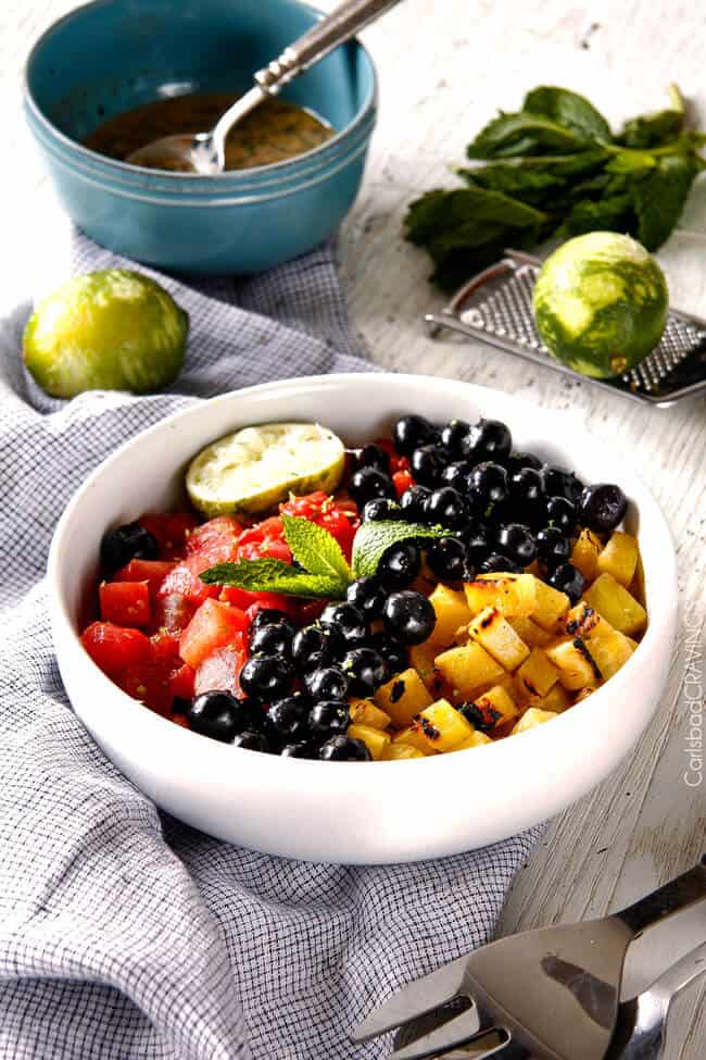side view of the best Summer Fruit Salad in a white bowl with Honey Lime Mint Dressing