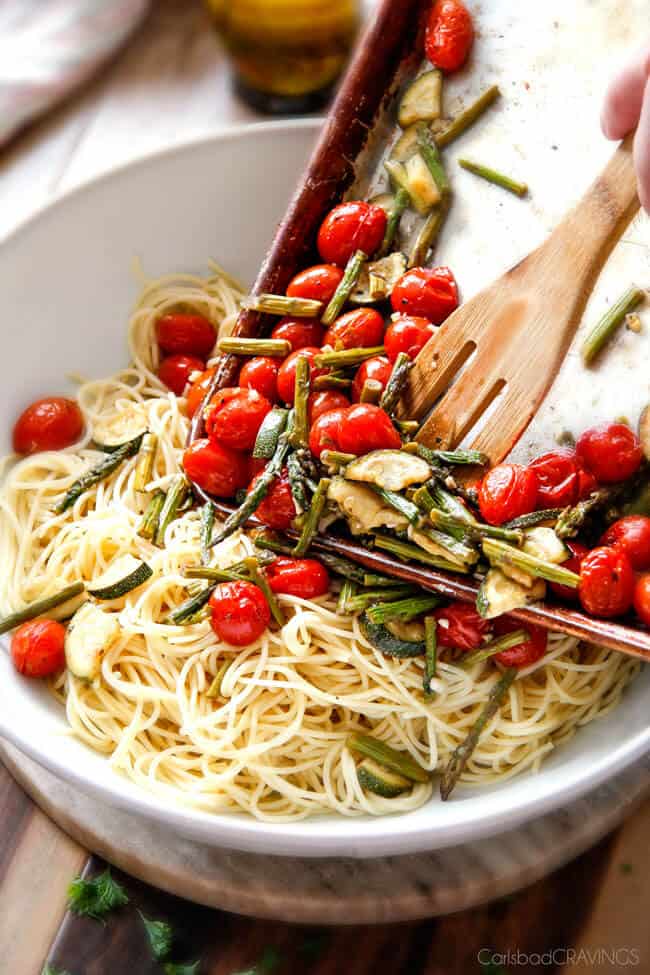 Showing how to make Caprese Chicken Pasta in adding ingredients in a bowl. 