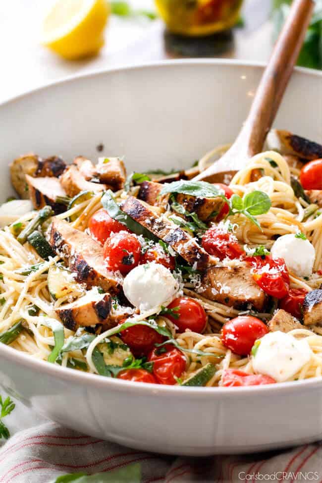 Caprese Chicken Pasta in a bowl with serving spoons. 