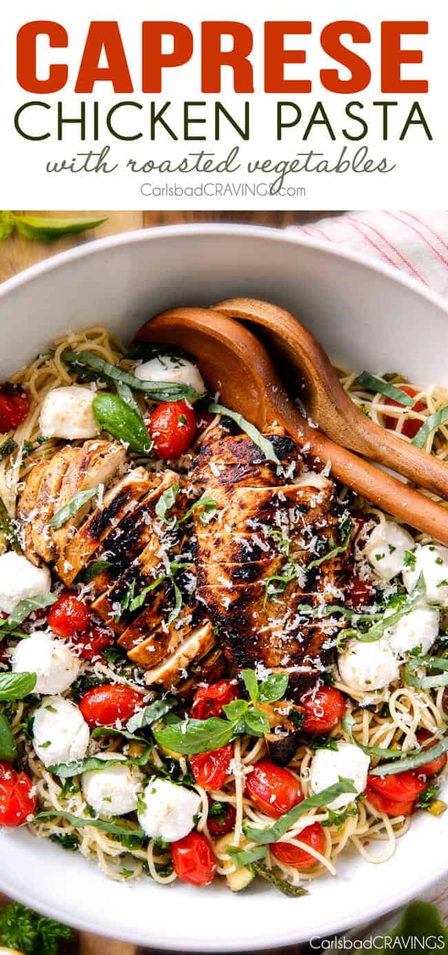 Caprese Chicken Pasta in a bowl with two wooden serving spoons. 
