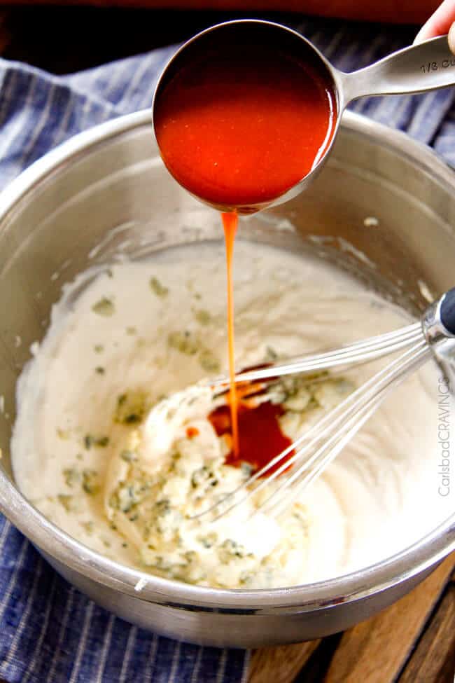 Showing how to make the filling for Buffalo Chicken Dip (Stuffed French Bread) by adding hot sauce. 