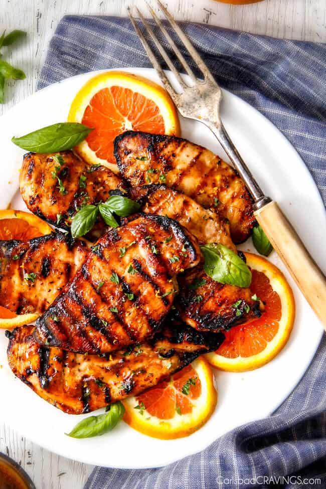 Chipotle Maple Chicken with grill marks on a plate with oranges. 