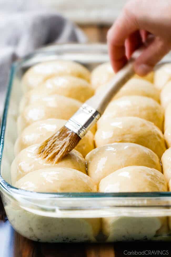 Showing how to make Hawaiian Sweet Rolls baked in a pan adding butter before baking.