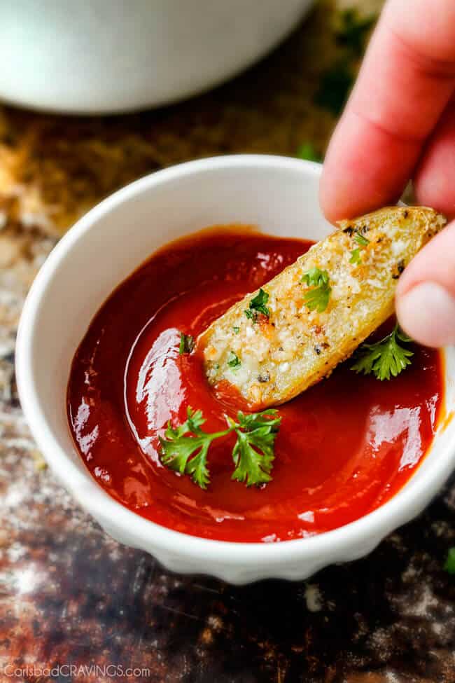 Dipping a Baked Parmesan Fingerling Potato Fries in ketchup. 