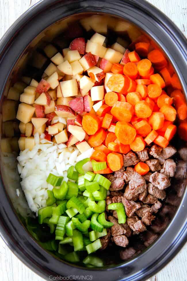 showing how to make Slow Cooker Beef Stew by adding beef, potatoes, carrots, celery, onions and garlic to crockpot. !