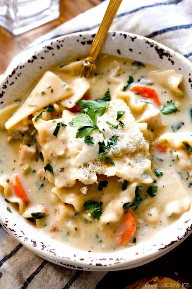 White Chicken Lasagna Soup in a bowl with parsley and cheese on top. 