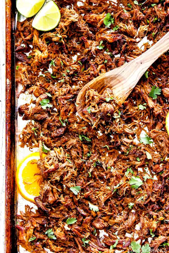 Mexican carnitas meat on sheet pan with wooden spoon showing  how to  make crispy 