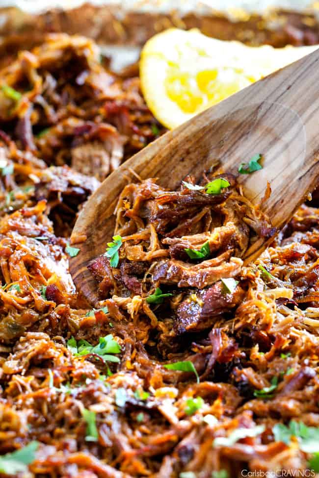 close up of wooden spoon scooping out portion of pork carnitas to  show how  crispy they are