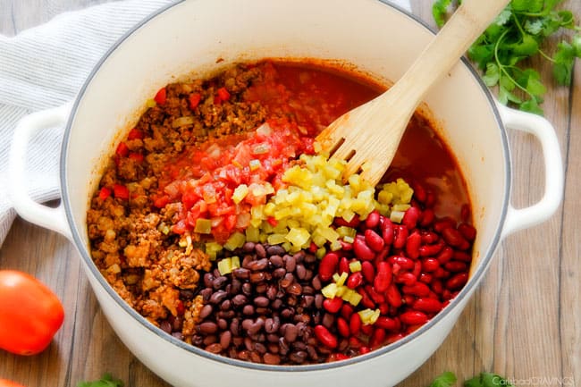 showing how to make Taco Soup by adding black beans, kidney beans,  enchilada sauce, salsa, green chilies, and chicken broth to white soup pot.